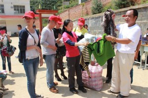 3上海爱心人士王扬女士（右二）与黑颈鹤保护志愿者协会副主席牟延安（右一）向孩子们发放爱心衣物。